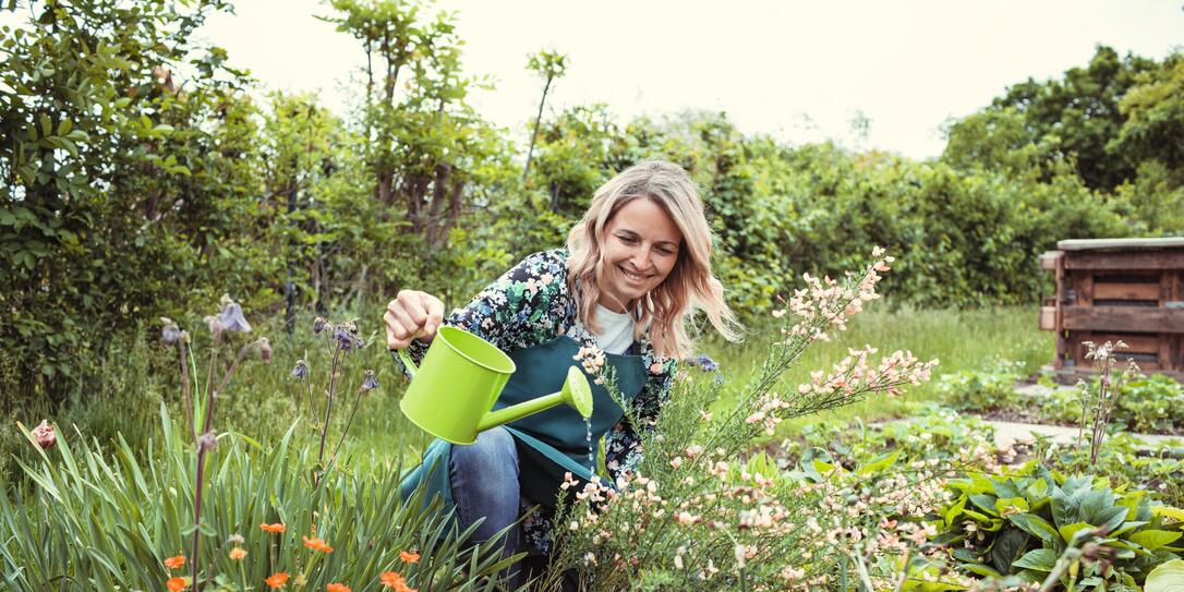 pretty blonde gardener working in garden with flowers