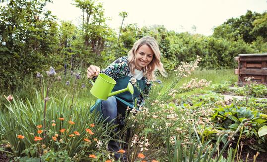 pretty blonde gardener working in garden with flowers