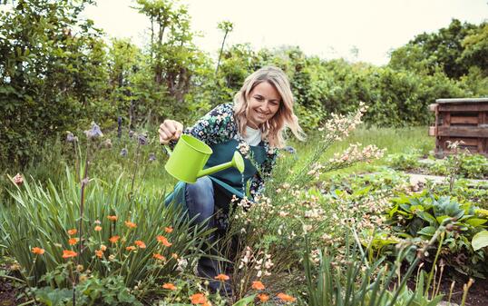 pretty blonde gardener working in garden with flowers