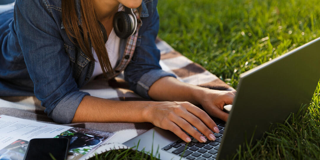 Beautiful young woman student in the park using laptop computer.
