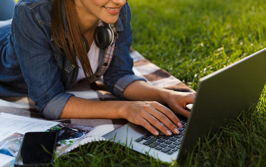 Beautiful young woman student in the park using laptop computer.