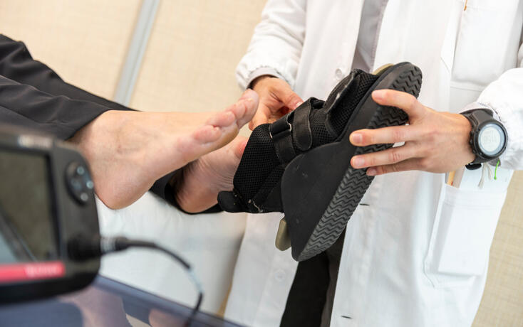 Doctor Fitting an Orthopedic Shoe During a Consultation