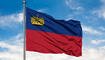 Flag of Liechtenstein waving in the wind against white cloudy blue sky.