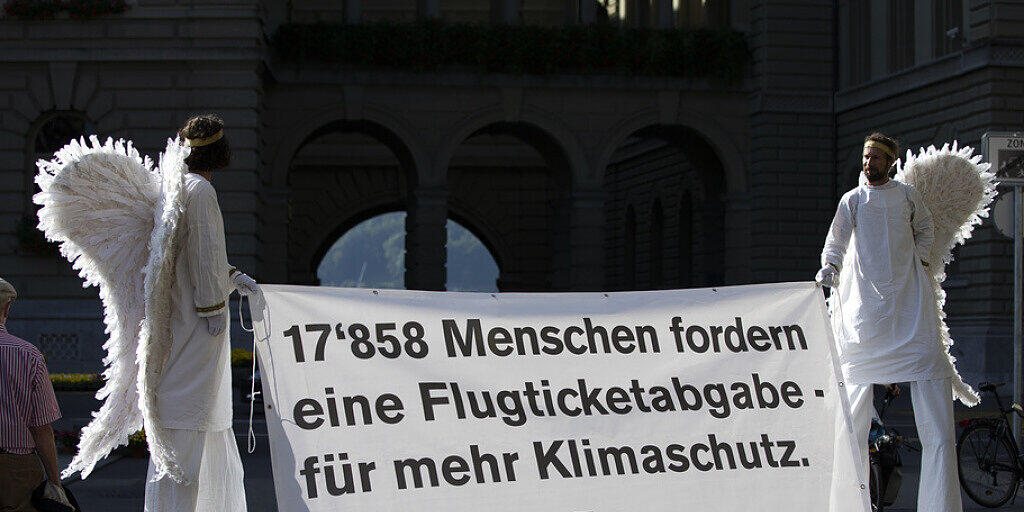 Aktivisten im Engelskostüm tragen am Dienstag ein Banner für die Petition "Ja zur Flugticketabgabe" vor das Bundeshaus.