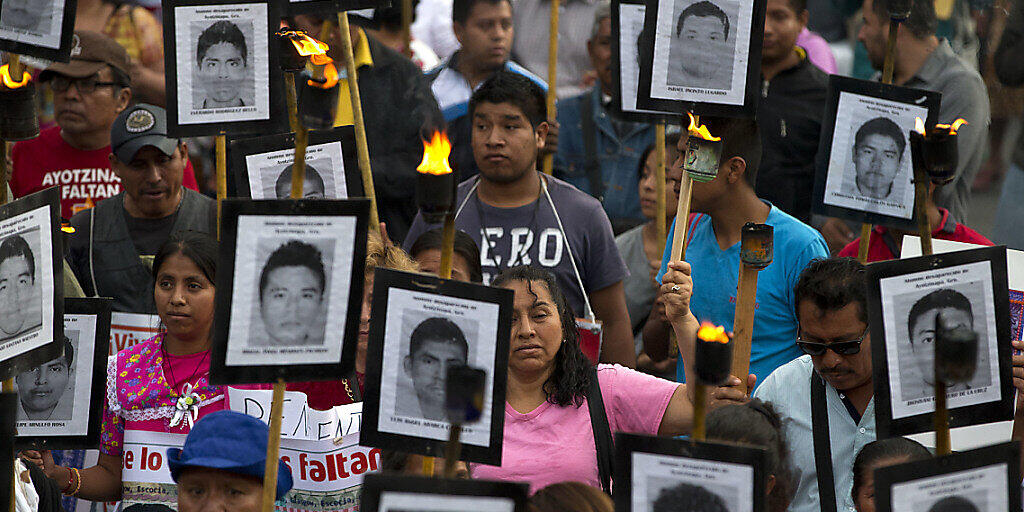 ARCHIV - Angehörige und Unterstützer tragen bei einem Protest-Marsch in Mexiko-Stadt im April 2016 Bilder der 43 vermissten Studenten. Foto: Rebecca Blackwell/AP/dpa