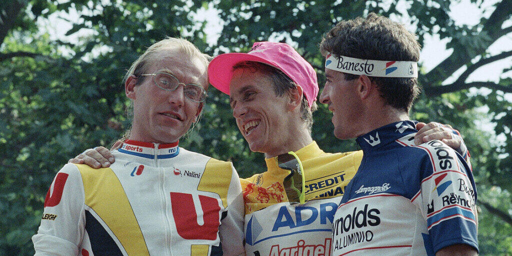 Greg LeMond (Mitte) versucht den geschlagenen Laurent Fignon (links) aufzumuntern; Pedro Delgado wurde Gesamtdritter