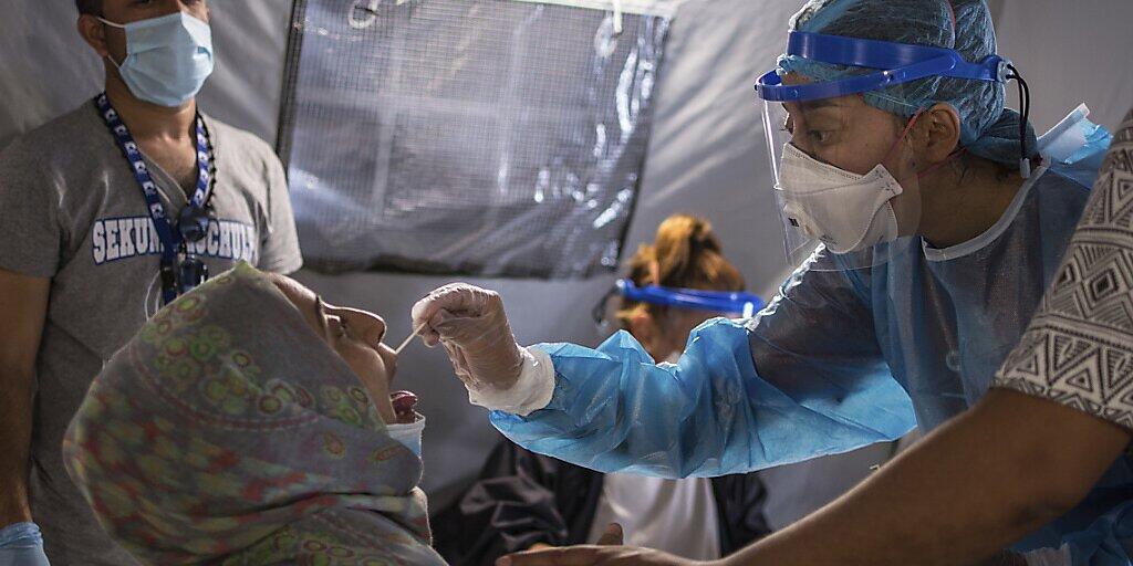 ARCHIV - Im Flüchtlingslager Moria wird einer Frau ein Abstrich aus dem Mund entnommen, um einen Corona-Test durchzuführen. Foto: Panagiotis Balaskas/AP/dpa
