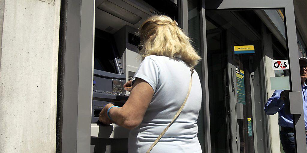 Ein Frau hebt an einem Bancomaten in Athen Geld ab - die Griechen haben laut griechischen Medienberichten allein vom 3. bis zum 5. Juni mehr als 1,2 Milliarden Euro von ihren Konten abgehoben (Archiv)