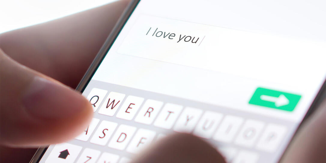Sending I love you text message with mobile phone. Online dating, texting or catfishing concept. Romance fraud, scam or deceit with smartphone. Man writing comment. Sending I love you text message with mobile phone. Online dating, texting or catfishing concept. Romance fraud, scam or deceit with smartphone. Man writing comment.
