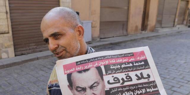Ein Mann trägt in Kairo eine Zeitung mit Mubarak auf der Titelseite Ein Mann trägt in Kairo eine Zeitung mit Mubarak auf der Titelseite