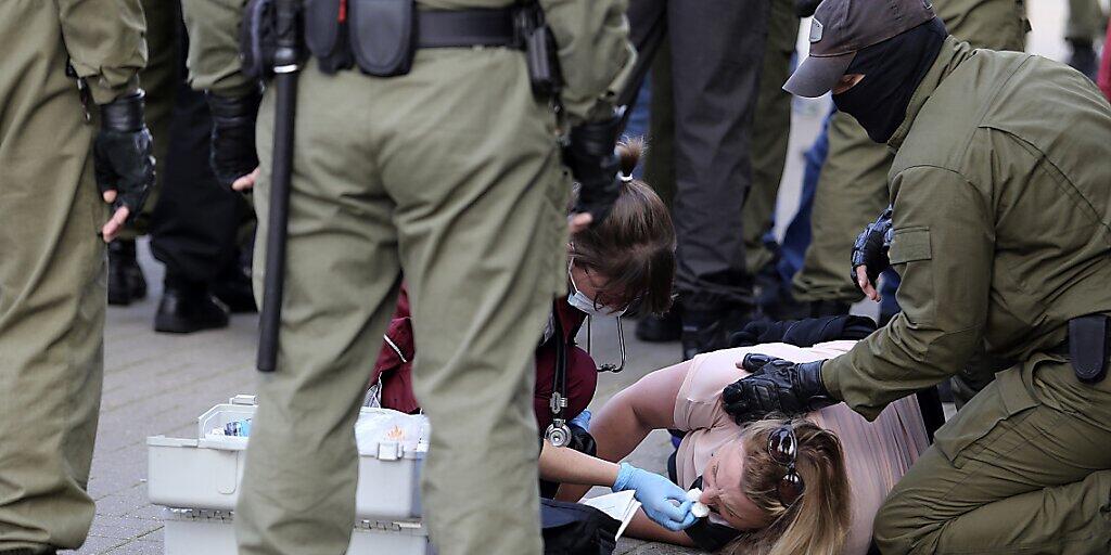 Eine Notärztin kümmert sich am Rande einer Demonstration gegen die Wahlergebnisse in Belarus um eine verletzte Frau, die neben Polizeibeamten auf dem Boden liegt. Foto: Uncredited/TUT.by/dpa