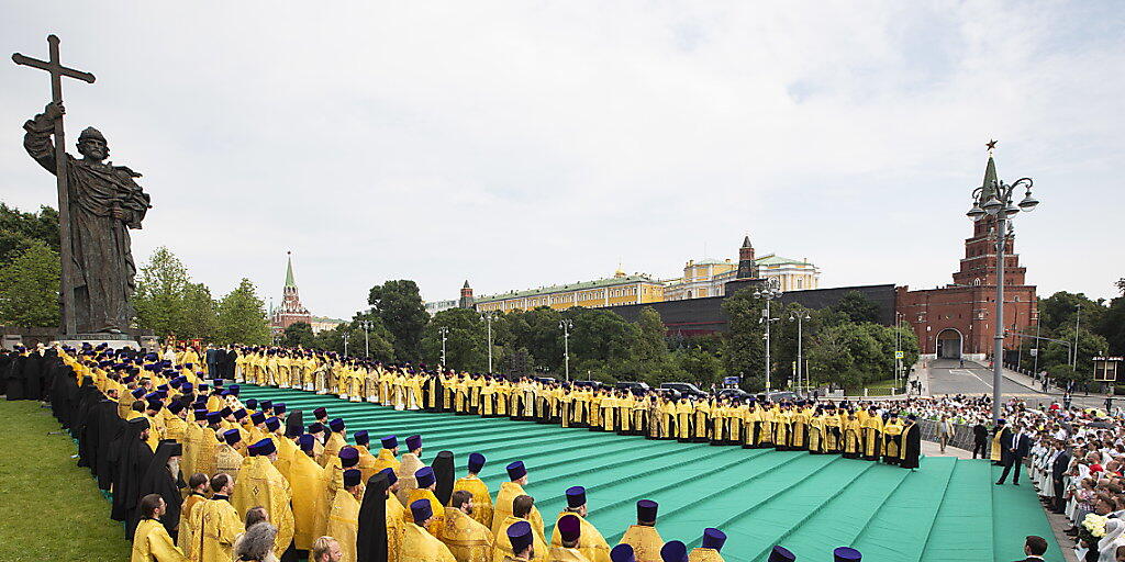 Die Taufe der Rus: Orthodoxe Priester an einer Zeremonie vor einer Statue von Fürst Wladimir in Moskau.