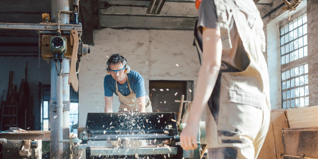 Team of carpenters planning wood using a machine