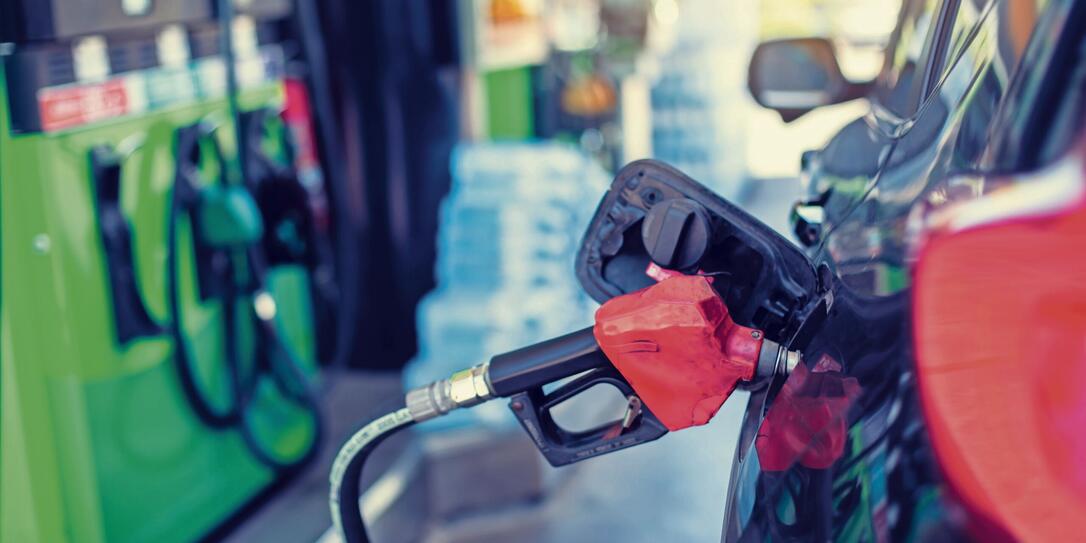 Selective focus to old red fuel nozzle with blurry fuel dispenser in gas station.
