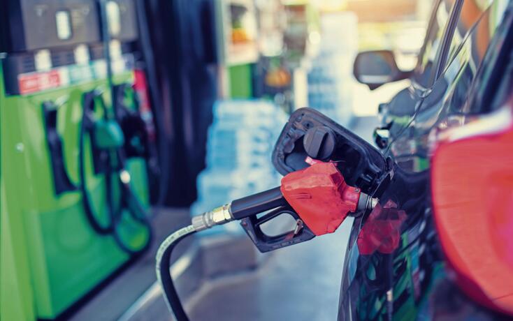 Selective focus to old red fuel nozzle with blurry fuel dispenser in gas station.