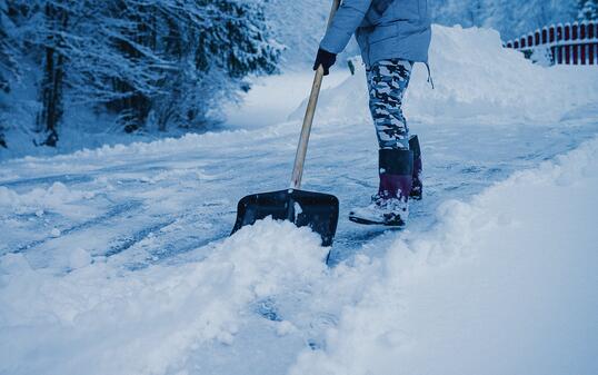 Woman tearing snow infront of the house