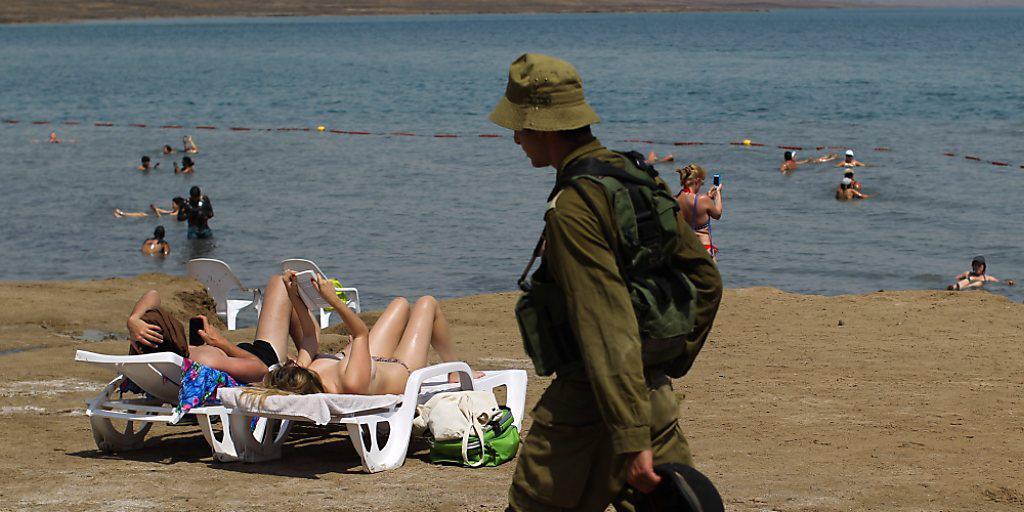 Israelische Soldaten patrouillieren entlang der Küste des Toten Meeres, während Touristinnen am Strand liegen. (Archivbild)