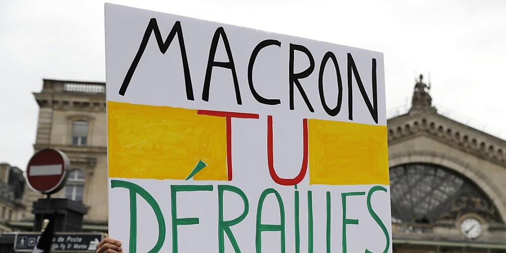 "Macron, du spinnst" heisst es auf einem Protestschild vor der Gare de l'Est  in Paris - in einem Wortspiel mit "le rail", deutsch: "die Schiene, das Gleis".