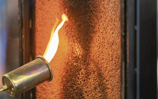 Close up of a flame torch testing flame retardant material, demonstrating fire resistance and safety in industrial applications