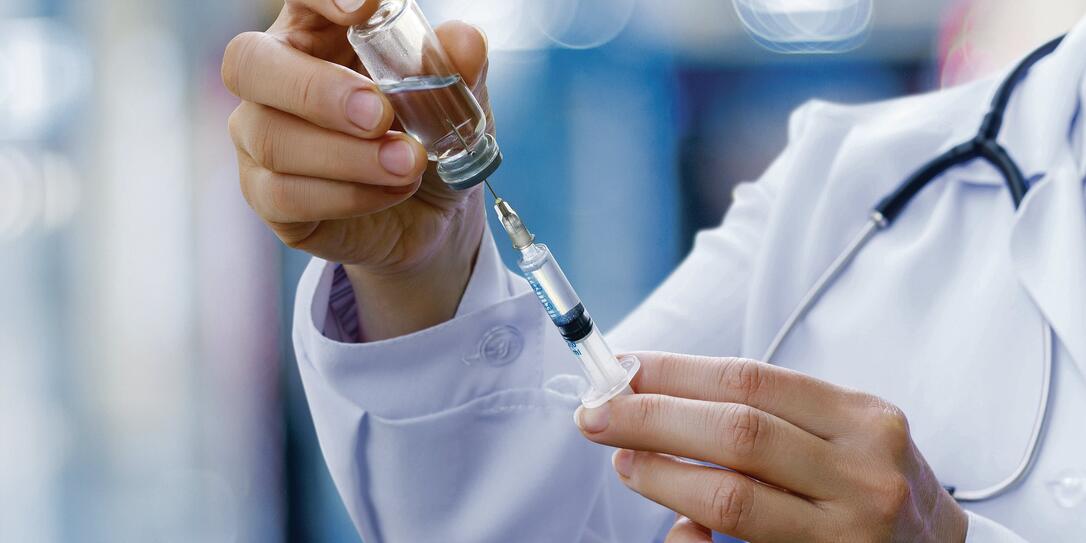 The doctor prepares the syringe for vaccination.