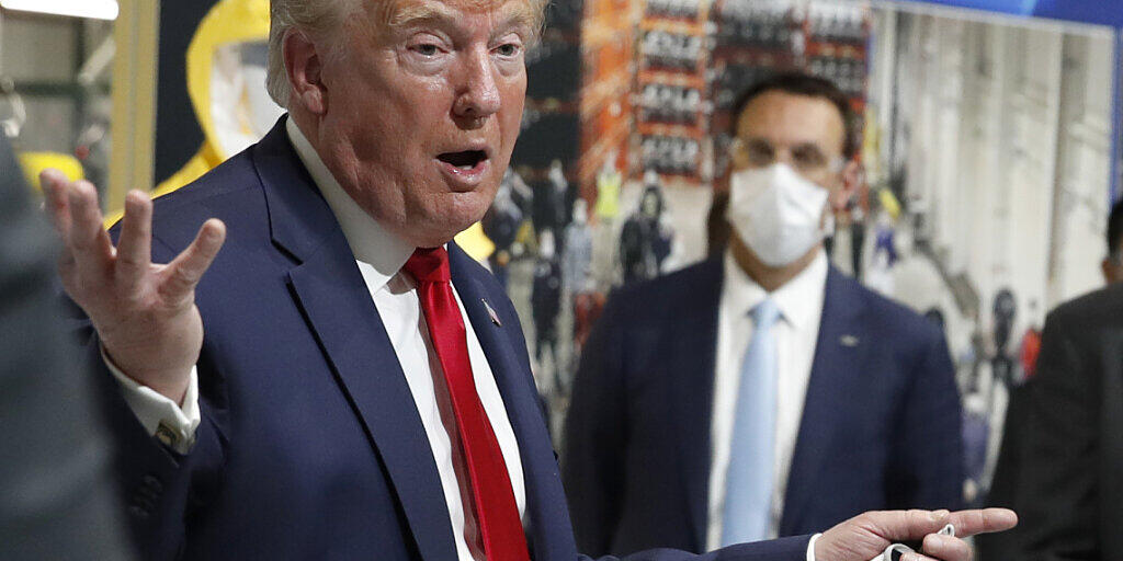 US-Präsident Donald Trump hat bei einem Besuch eine Fabrik in Michigan trotz Maskenpflicht erneut zumindest teilweise keine Schutzmaske getragen. Auf dem Bild hält er zwar eine Maske in der Hand, setzt sie aber nicht auf.