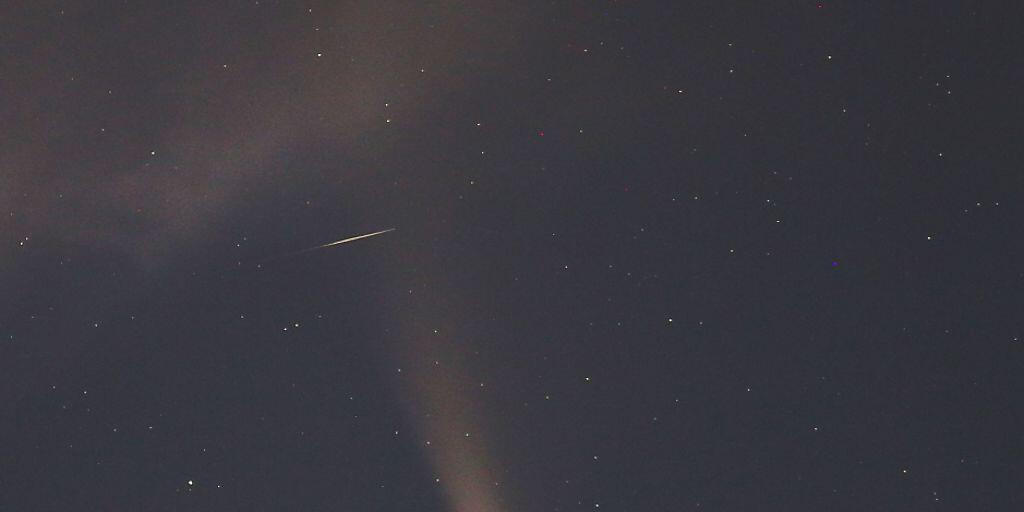 Eine Sternschnuppe zischt quer durch den Schweif des Kometen und hinterlässt eine kurze Strichspur auf dem Foto. (Bild vom 18. Juli)