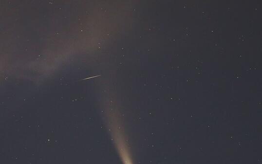Eine Sternschnuppe zischt quer durch den Schweif des Kometen und hinterlässt eine kurze Strichspur auf dem Foto. (Bild vom 18. Juli)