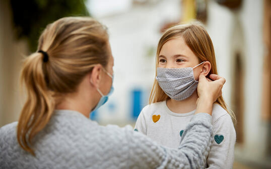 A mother helps daughter put home made face mask for COVID-19