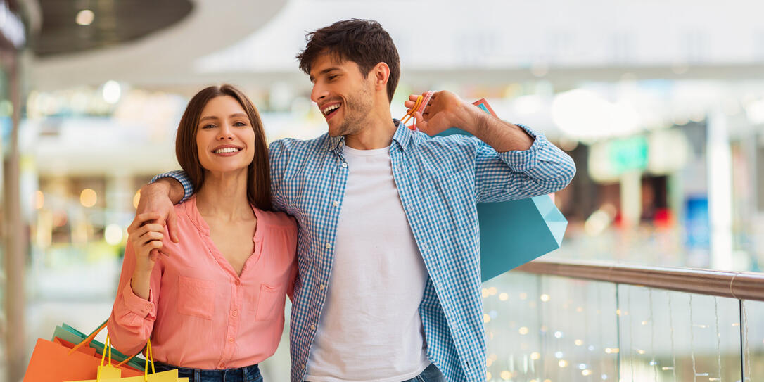 Happy Couple Hugging Doing Shopping Walking Together In Hypermarket