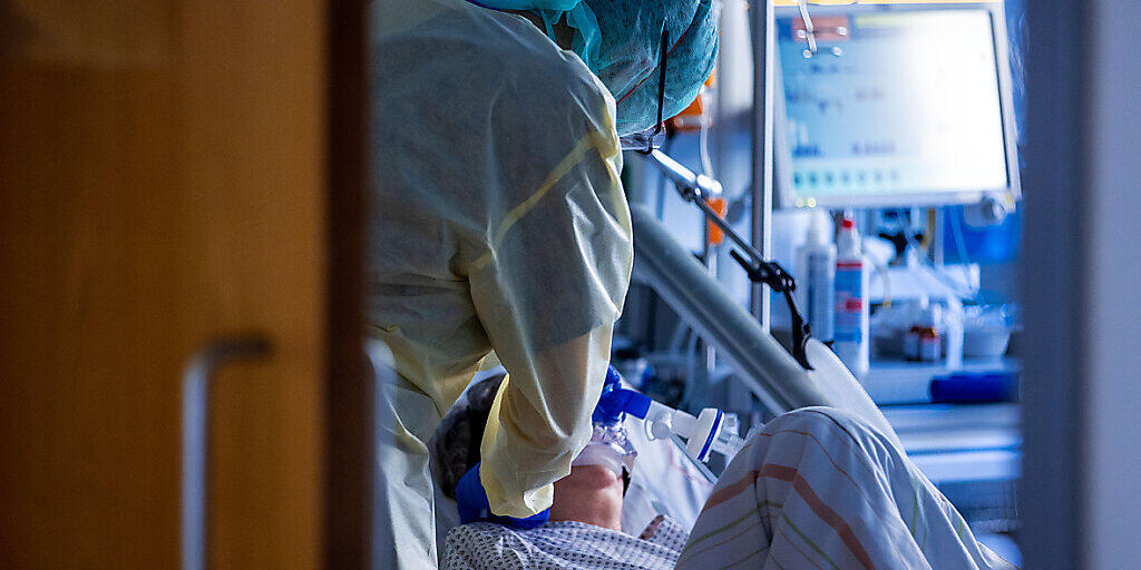 ARCHIV - Eine Pflegekraft versorgt im besonders geschützten Teil der Intensivstation des Universitätsklinikums einen Corona-Patienten. Foto: Jens Büttner/dpa-Zentralbild/dpa