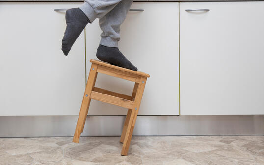 A man falls off a small kitchen ladder