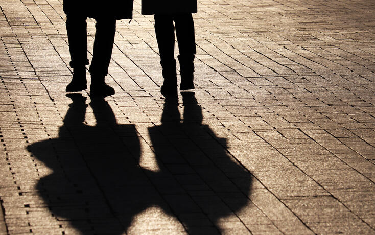 Two women walking down the street, silhouettes and shadows on pavement