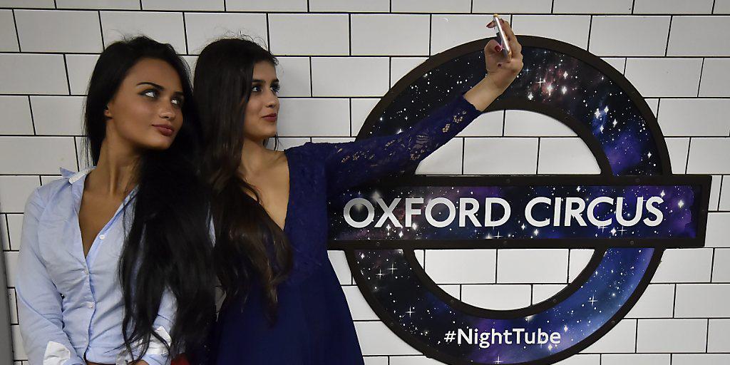 Neben einen Zug: Zwei Nachtschwärmerinnen in London nutzen die U-Bahn, die neuerdings an Wochenenden rund um die Uhr fährt.