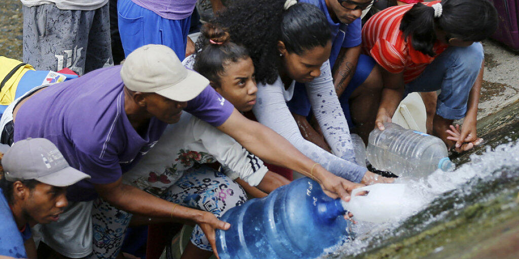 Prekäre Wasserversorgung in Venezuela wegen des Stromausfall: Menschen in der Hauptstadt Caracas holen sich Wasser bei einer leckgeschlagenen Leitung.