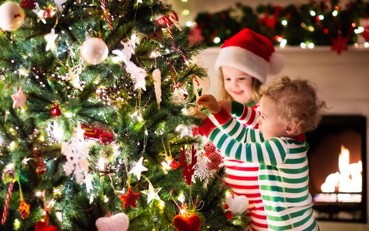 Kids decorating Christmas tree in beautiful living room