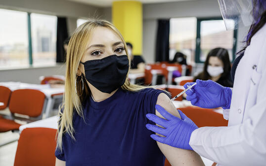Nurse gives students a vaccination in school during coronavirus pandemic
