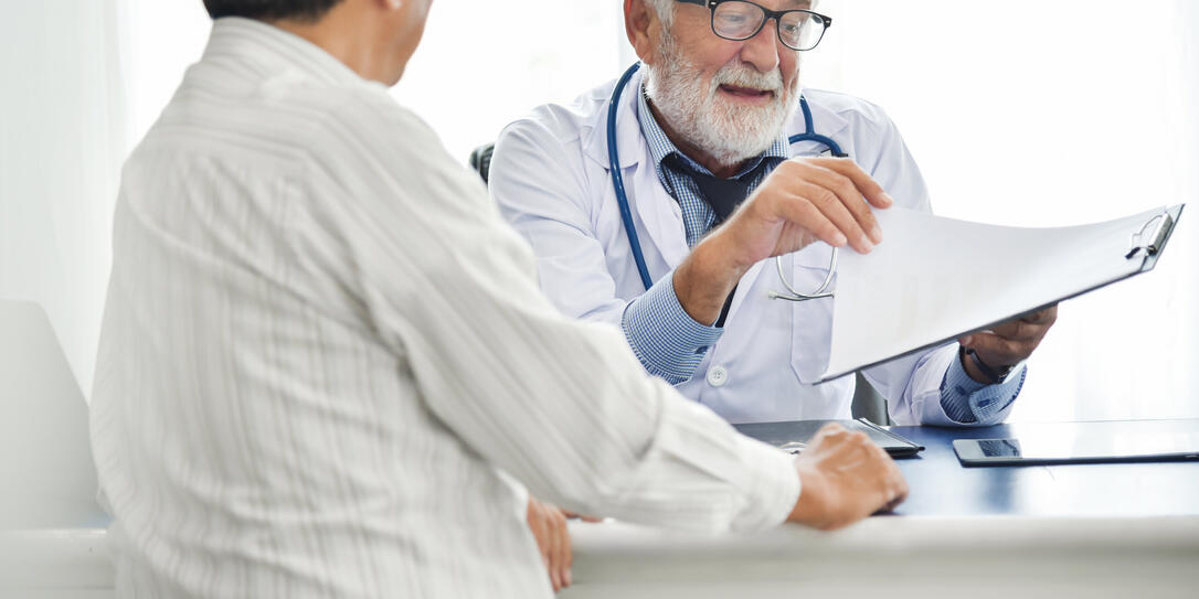 Senior male Doctor is discussing with Asian male patient.