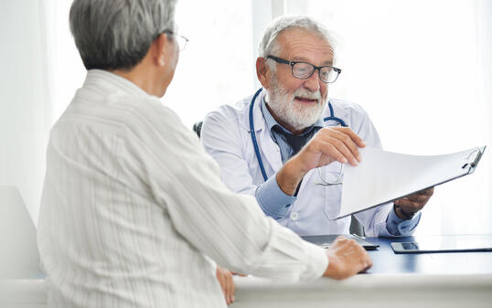 Senior male Doctor is discussing with Asian male patient.