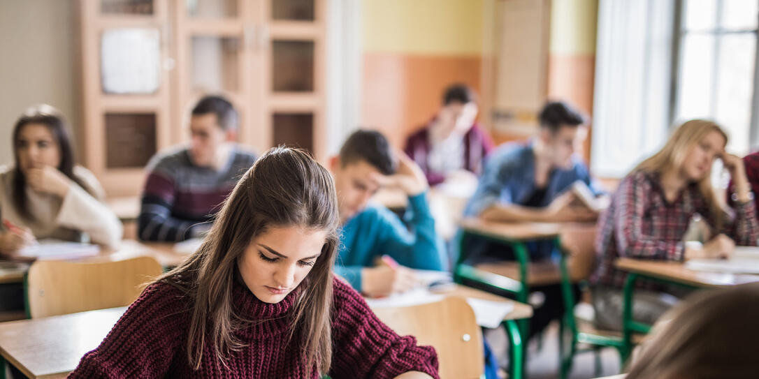 Female high school student writing a test in the classroom. Female high school student writing a test in the classroom.