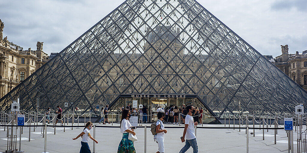ARCHIV - Eine Familie mit Schutzmasken geht am Louvre vorbei. (zu dpa "Corona-Krise: Frankreich kommt seinen großen Museen zu Hilfe") Foto: Kamil Zihnioglu/AP/dpa
