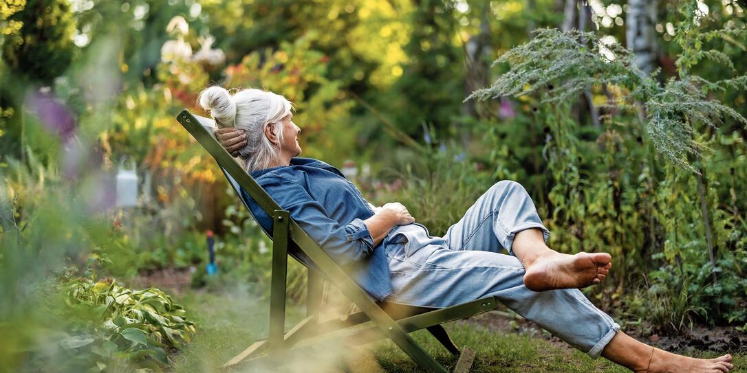 Mature woman relaxing in deckchair in her garden