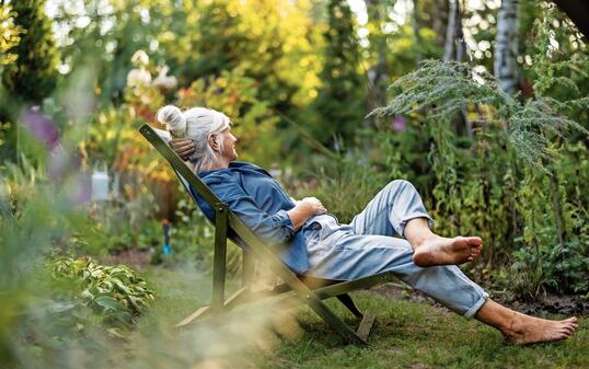 Mature woman relaxing in deckchair in her garden
