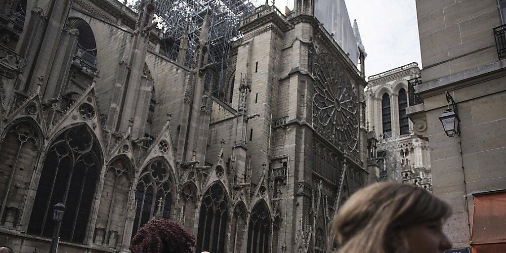 Touristen sehen sich gut eine Woche nach dem verheerenden Brand den Schaden an der Kathedrale Notre-Dame an.  Am Dienstag wurde begonnen, eine Plane auf der mehr als 850 Jahre alten Kathedrale anzubringen, deren Dach in grossen Teilen zerst&ouml;rt wurde. (Archivbild)