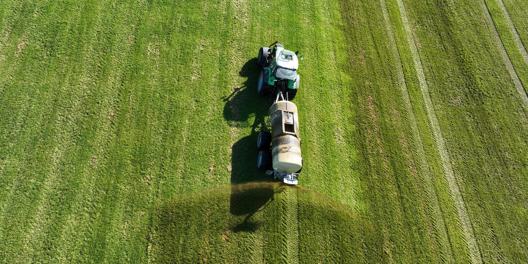 Drone image of a tractor spreading liquid manure or slurry on a field
