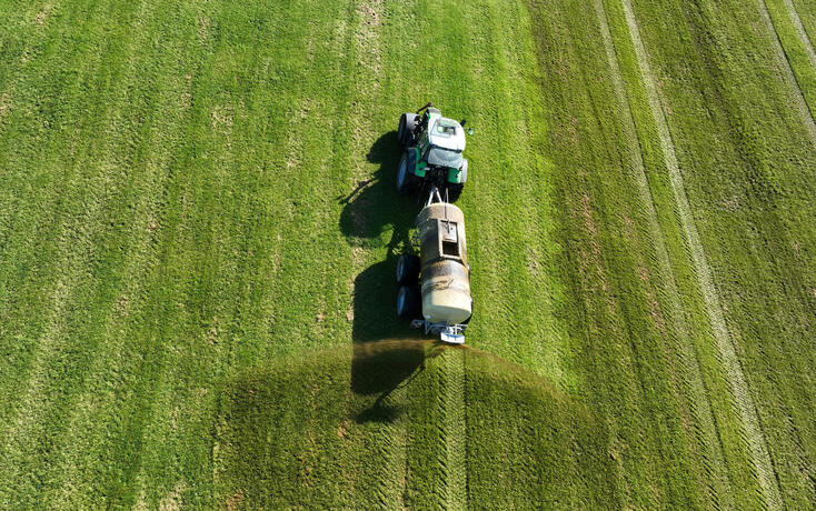 Drone image of a tractor spreading liquid manure or slurry on a field
