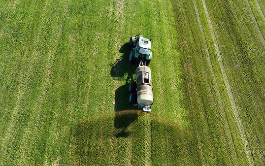 Drone image of a tractor spreading liquid manure or slurry on a field