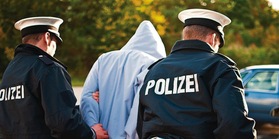 Two police officers are frogmarching a suspect