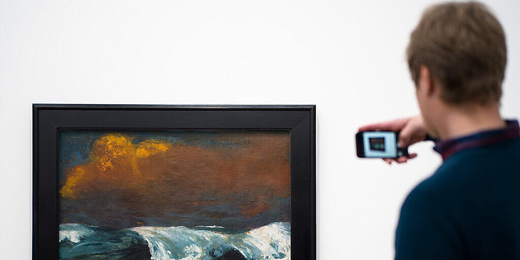 Ein Ausstellungsbesucher macht ein Foto von Emil Noldes Gemälde "Brecher" von 1936. Emil Nolde (1867-1956) ist eine Ikone des Expressionismus. Er war aber auch Unterstützer des Nationalsozialismus. eine Ausstellung in Berlin setzt sich kritisch mit seinem Werk auseinander. (Archiv) Ein Ausstellungsbesucher macht ein Foto von Emil Noldes Gemälde "Brecher" von 1936. Emil Nolde (1867-1956) ist eine Ikone des Expressionismus. Er war aber auch Unterstützer des Nationalsozialismus. eine Ausstellung in Berlin setzt sich kritisch mit seinem Werk auseinander. (Archiv)