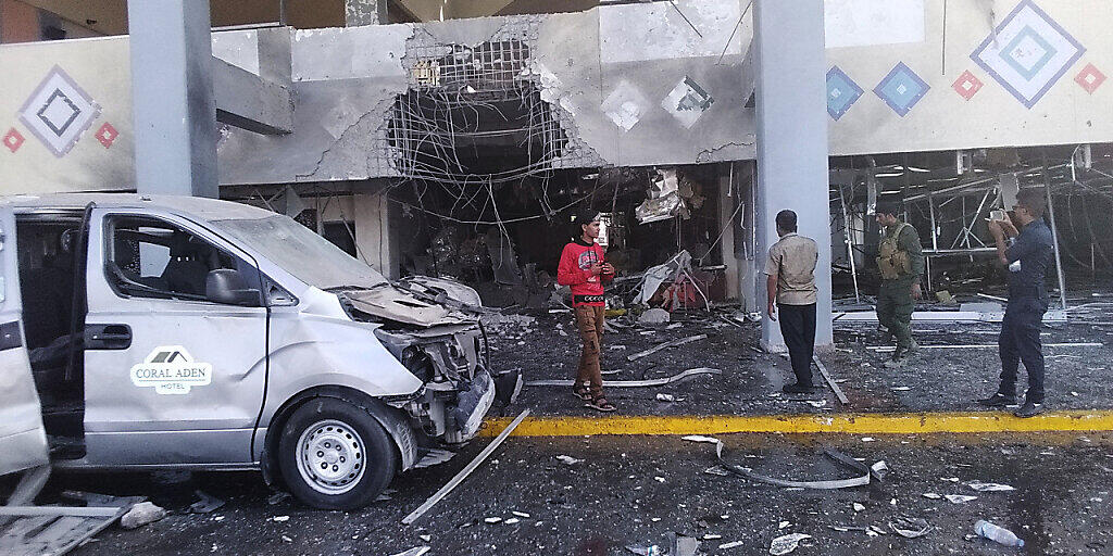 Menschen stehen in der Nähe eines beschädigten Gebäudeteils des Flughafens nach einer Explosion. Die Explosion traf das Flughafengebäude. Foto: Majid Saleh/AP/dpa