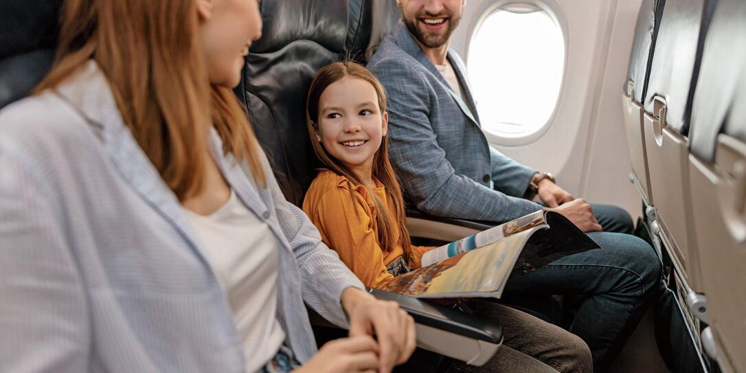 Cheerful little girl traveling with parents on airplane